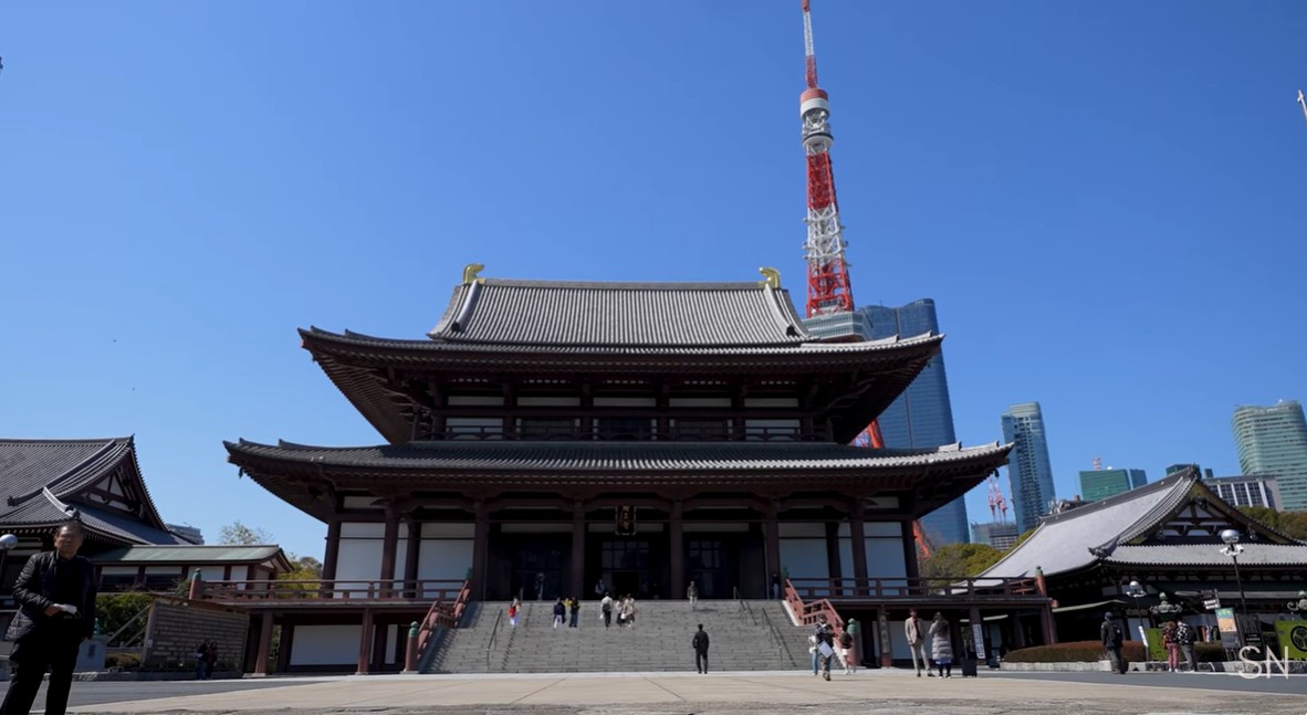 Zojo-ji Temple with Tokyo Tower rising prominently behind it against a clear blue sky